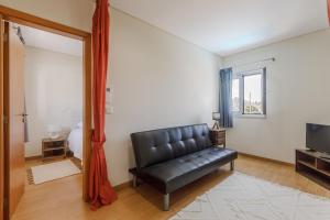 a living room with a black leather couch and a television at Casa das Agras in Souto