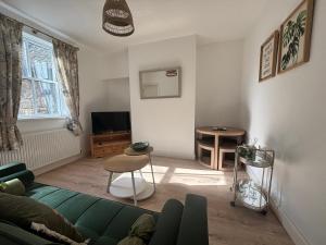a living room with a green couch and a table at Crown Cottage in Belper