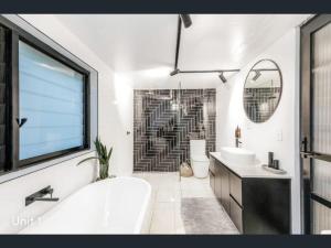 a bathroom with a tub and a sink and a mirror at A spacious Family Retreat near the Beach in Cronulla +47 photos