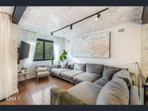 a living room with a couch and a tv at A spacious Family Retreat near the Beach in Cronulla