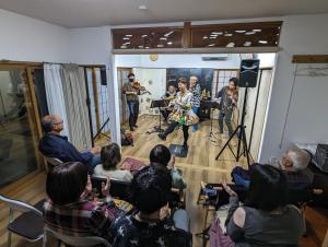 a group of people watching a band playing in a room at ゲストハウスきーず in Nishio
