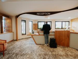 a man standing at a reception desk in a lobby at Hotel Restaurant Au Parc des Cigognes in Kintzheim