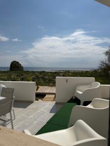 a patio with white chairs and a green carpet at Andrew'S home - Playita in Torre Pali