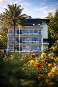 a building with a palm tree and a field of flowers at Mount Minar Munnar in Anachal