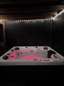 a bath tub filled with pink water and lights at Sun Set House With Hot Tub in Witchford +25 photos
