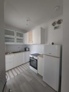 a white kitchen with white cabinets and a stove top oven at Varkiza Pines Apartment in Varkiza