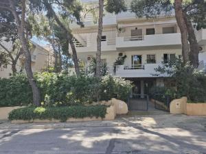 a building with trees and bushes in front of it at Varkiza Pines Apartment in Varkiza