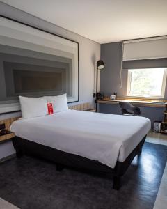 a bedroom with a large white bed with a window at Ibis Monterrey Aeropuerto in Monterrey +81 photos