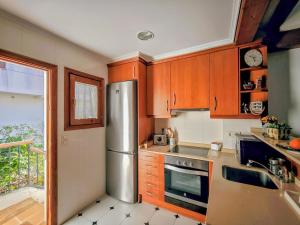 a kitchen with wooden cabinets and a stainless steel refrigerator at Beachfront in Denia Alicante in Denia