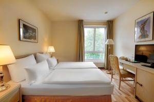 a hotel room with a large white bed and a desk at Hotel am Schloß Köpenick by Golden Tulip in Berlin +195 photos