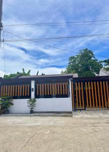 a white house with a black and yellow gate at Maria Staycation House in Davao City