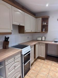 a kitchen with white cabinets and a stove top oven at The Barn With A View in Portskewett
