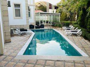a swimming pool in a yard with chairs and a house at Turkiye Hotel - Free Massage - Free Swimming Pool in Baku