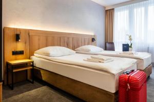 two beds in a hotel room with a red suitcase at Hotel Zawisza in Bydgoszcz