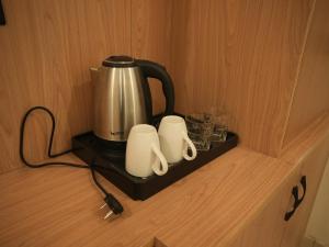 a coffee pot and two cups on a shelf at The RaaS Guestline in Noida