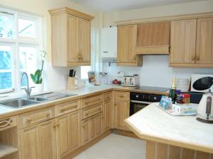 a kitchen with wooden cabinets and a sink at 4 Bed in Swanage oc-dc046 in Studland