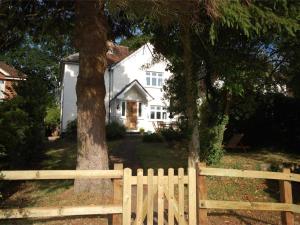 a white house with a wooden fence and trees at 4 Bed in Swanage oc-dc046 in Studland +9 photos