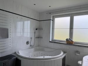 a white bathroom with a tub and a window at Apartment Alpen Lodge 52 in Aschau +14 photos