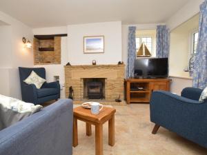 a living room with two blue chairs and a fireplace at 1 Bed in Bridport oc-dc085 in Loders