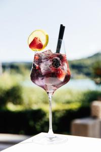 a glass with a drink with fruit in it at Hotel Villa Rainer in Pörtschach am Wörthersee