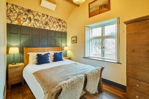 a bedroom with a bed with blue pillows and a window at Host & Stay - Kingbridge Forge in Lanercost
