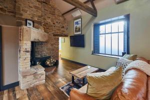 a living room with a couch and a stone fireplace at Host & Stay - Kingbridge Forge in Lanercost