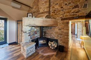 a stone fireplace in a room with a brick wall at Host & Stay - Kingbridge Forge in Lanercost