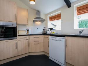 a kitchen with wooden cabinets and a white dishwasher at 1 Bed in Wareham oc-dc153 in Wool