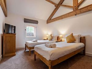 two beds in a room with a tv and a window at 3 Bed in Malton oc-75898 in Amotherby