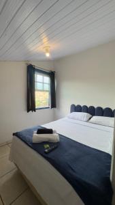 a bedroom with a large white bed with a window at Escadaria Vila Rica Pousada & Hostel in Ouro Preto