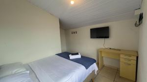 a bedroom with a bed and a desk with a television at Escadaria Vila Rica Pousada & Hostel in Ouro Preto