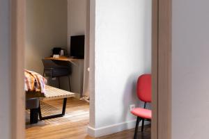 a room with a red chair and a desk at Hotel Linette in Aumont-Aubrac