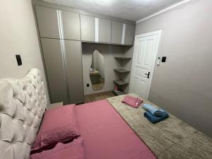 a bedroom with a pink bed with a mirror at Casa aconchegante em Olaria in Nova Friburgo