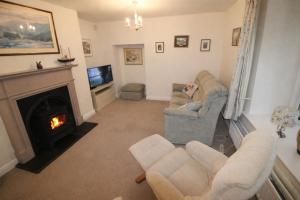 ein Wohnzimmer mit zwei Sesseln und einem Kamin in der Unterkunft Brookside, Hawkshead with garden and parking in popular village in Hawkshead