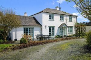 ein weißes Haus mit einem Tisch und Stühlen davor in der Unterkunft Brookside, Hawkshead with garden and parking in popular village in Hawkshead