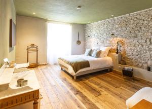 a bedroom with a bed and a stone wall at La Chaumée par L'émulsion in Saint-Alban-de-Roche