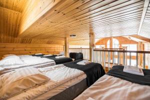 a row of beds in a room with wooden walls at Päijänteen Helmi 2 in Jämsä
