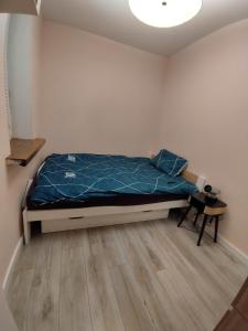 a bedroom with a bed with a blue comforter at Jolanta's apartment in Hajnówka