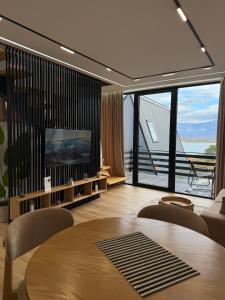 a living room with a table and a large window at Lakeside Villas & Jacuzzi Suites in Shirokë