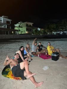 a group of people sitting on the beach at night at La Palma Hostel & Bar in Maragogi +43 photos