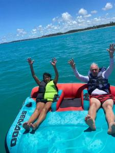 two people riding on a raft in the water at La Palma Hostel & Bar in Maragogi