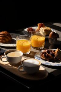 a table with plates of breakfast foods and glasses of orange juice at Hotel Linette in Aumont-Aubrac