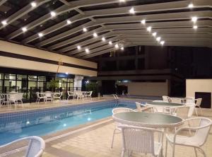 a pool with tables and chairs next to a swimming pool at Flat próximo ao Aeroporto Congonhas Piscina, Academia e Restaurante in São Paulo