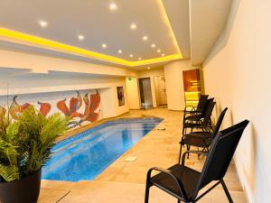 a swimming pool in a room with black chairs at ArdoVel Park Hotel in Velingrad +19 photos