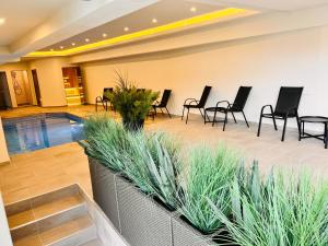 a swimming pool in a lobby with black chairs and tables at ArdoVel Park Hotel in Velingrad