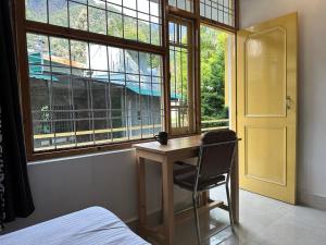 a bedroom with a desk and a chair next to a window at OmiHomeStay Dharamkot McLeodganj in Dharamshala