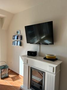 a living room with a fireplace with a flat screen tv on the wall at Fewo Schröder - BUDE 63a - mit Strandkorb am Meer - inklusive Bettwäsche und Handtücher in Westerdeichstrich +17 photos