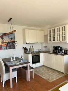 a kitchen with white cabinets and a table and a stove at Fewo Schröder - BUDE 63a - mit Strandkorb am Meer - inklusive Bettwäsche und Handtücher in Westerdeichstrich