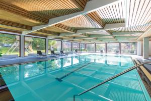 an indoor swimming pool with glass windows and a large ceiling at Hotel Hof Sudermühlen in Egestorf +19 photos