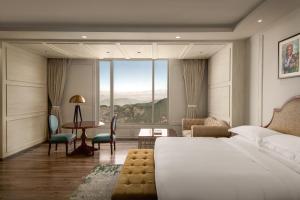 a bedroom with a bed and a desk and a large window at The Greenberry Mountain Resort Narkanda in Nārkanda